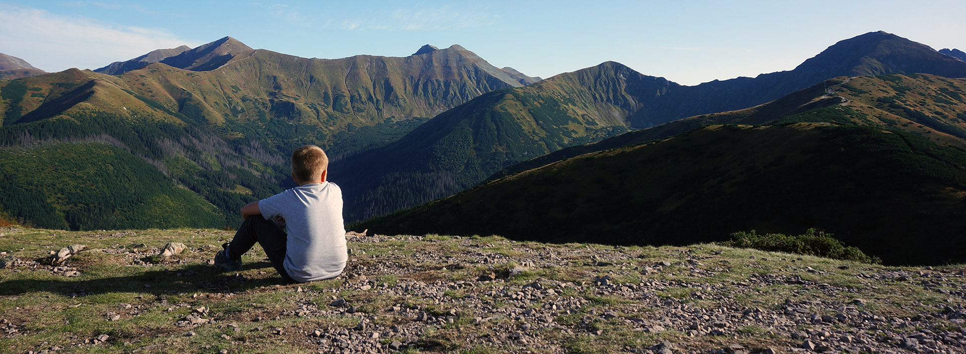 chłopiec siedzi tyłem i patrzy na panoramę tatr zachodnich