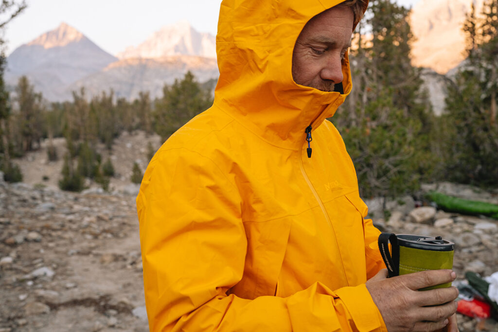 mężczyzna w żółtej kurtce GORE-TEX z kubkiem termicznym w ręce
