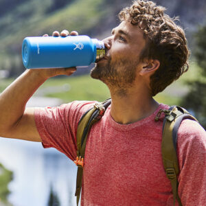 mężczyzna pijący z butelki hydroflask niebieskiej