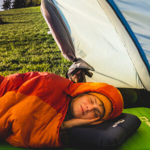 osoba spiąca w śpiworze wewnątrz namiotu