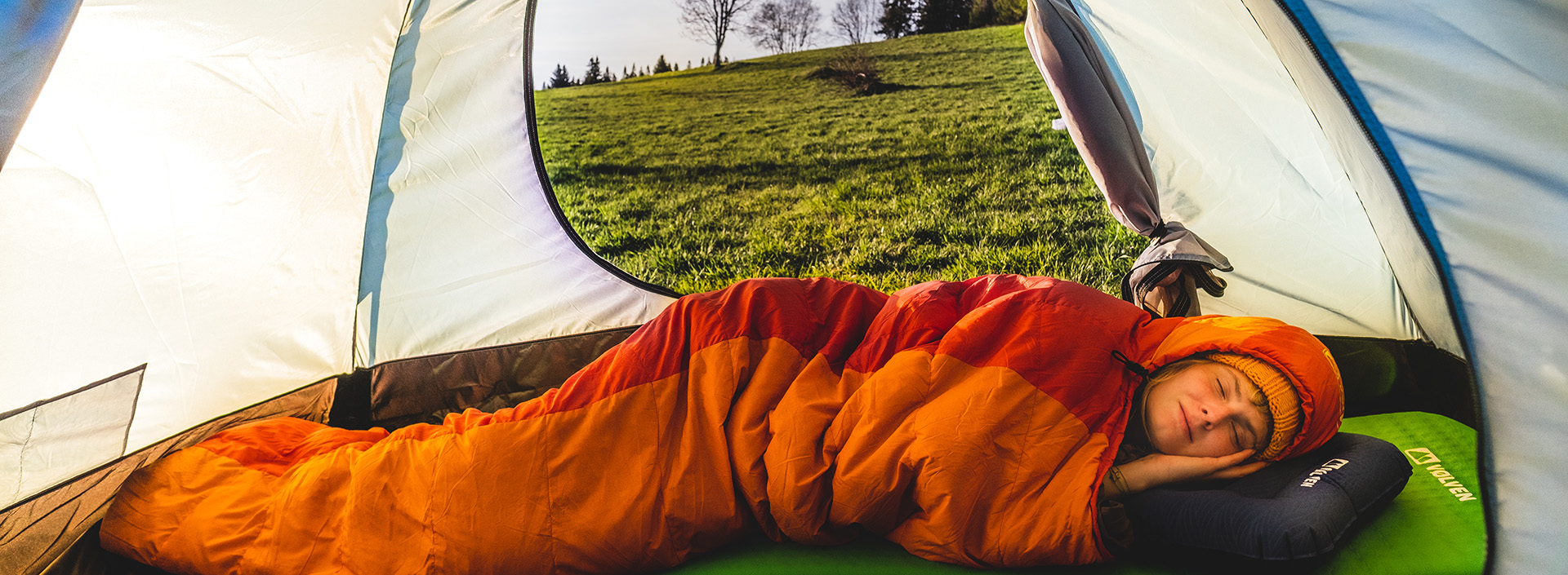 osoba spiąca w śpiworze wewnątrz namiotu