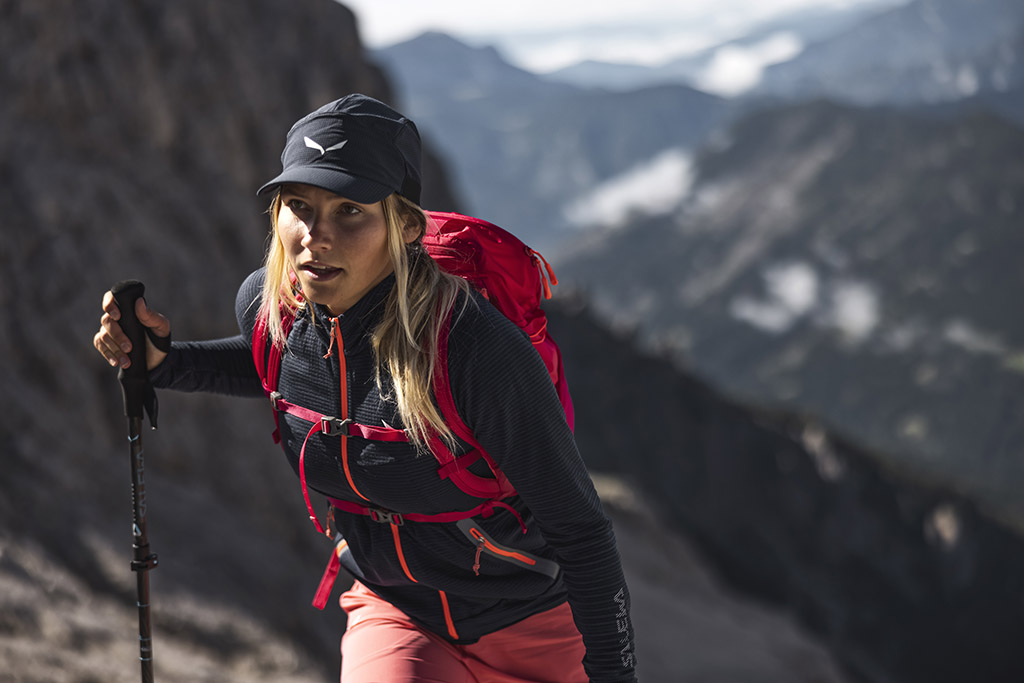Kobieta w górach opiera się na kijku trekkingowym