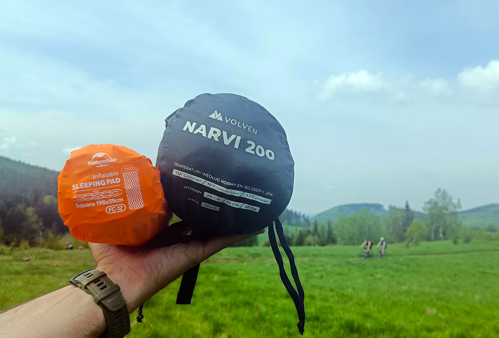 zwinięty śpiwór Narvi i materac FC-12 trzymane na dłoni