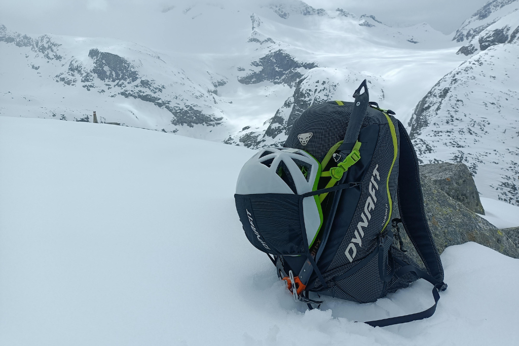 Kask zamocowany w wyciąganej siatce plecaka Dynafit — stabilne i wygodne rozwiązanie, które dobrze sprawdza się podczas podejść i transportu sprzętu.